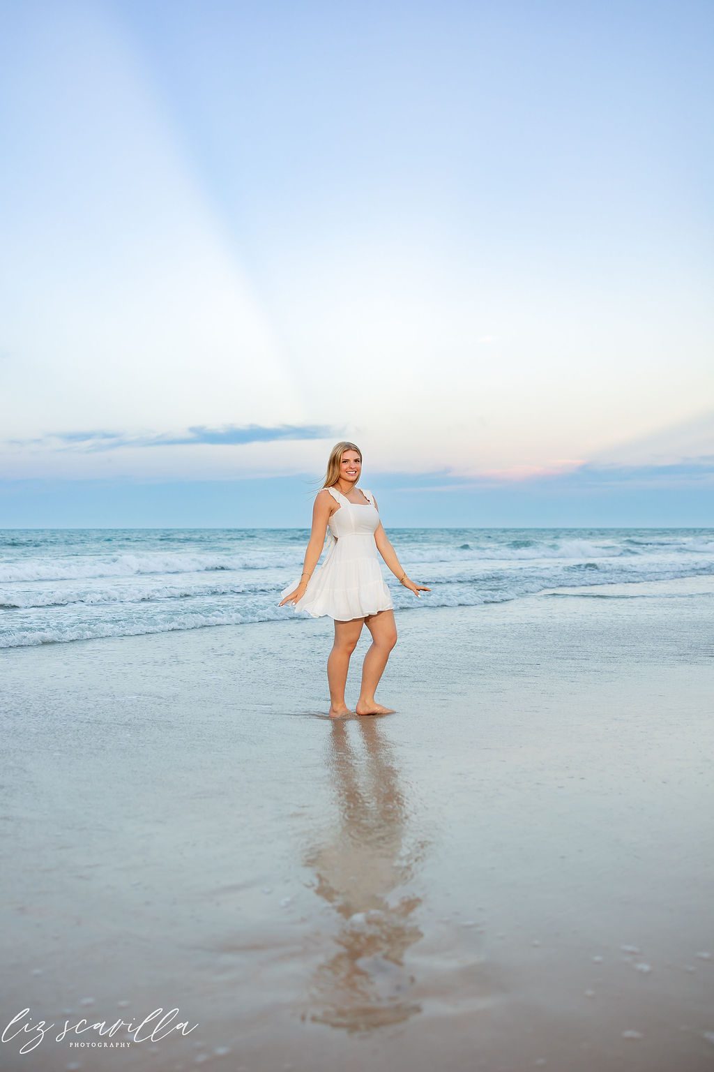 Ormond Beach senior photos of Ryann reflected in wet sand beneath a pastel sky