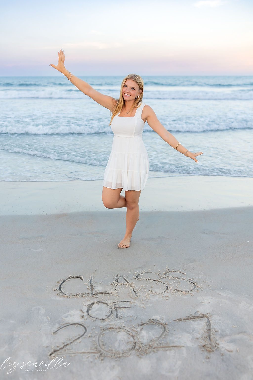 Ryann celebrating the Class of 2027 with the graduation year written in the sand