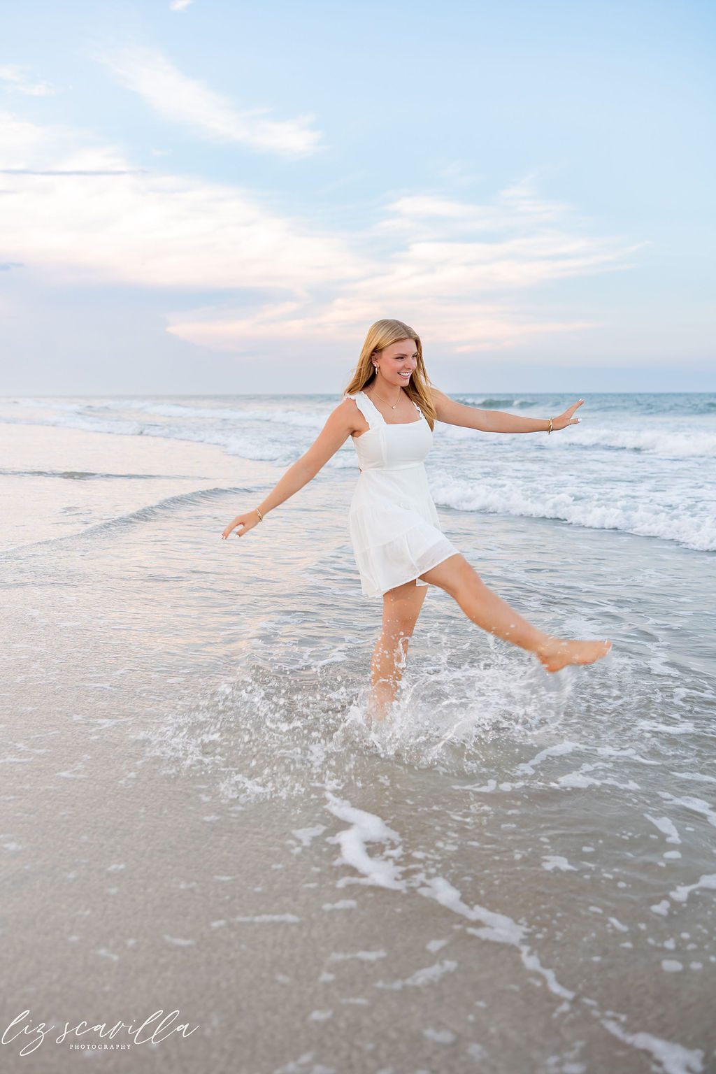 Ryann kicking her foot through the surf during her senior portrait session